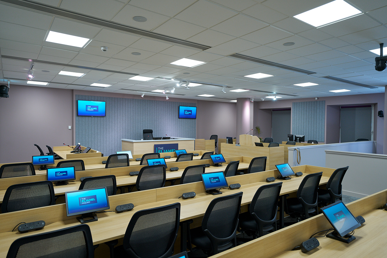 Rows of benches with chairs and small computer screens for legal personnel