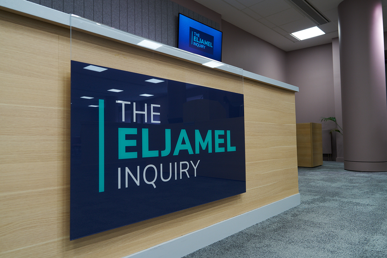 A large display of the Eljamel Inquiry logo inside hearing room